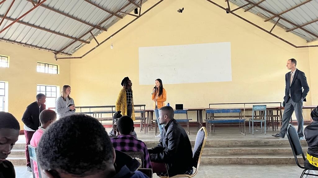 Lijie Zhou and Abisola Kusimo presenting at the front of a LOHADA classroom while Chuck Eesley stands to the side; students seated in the foreground